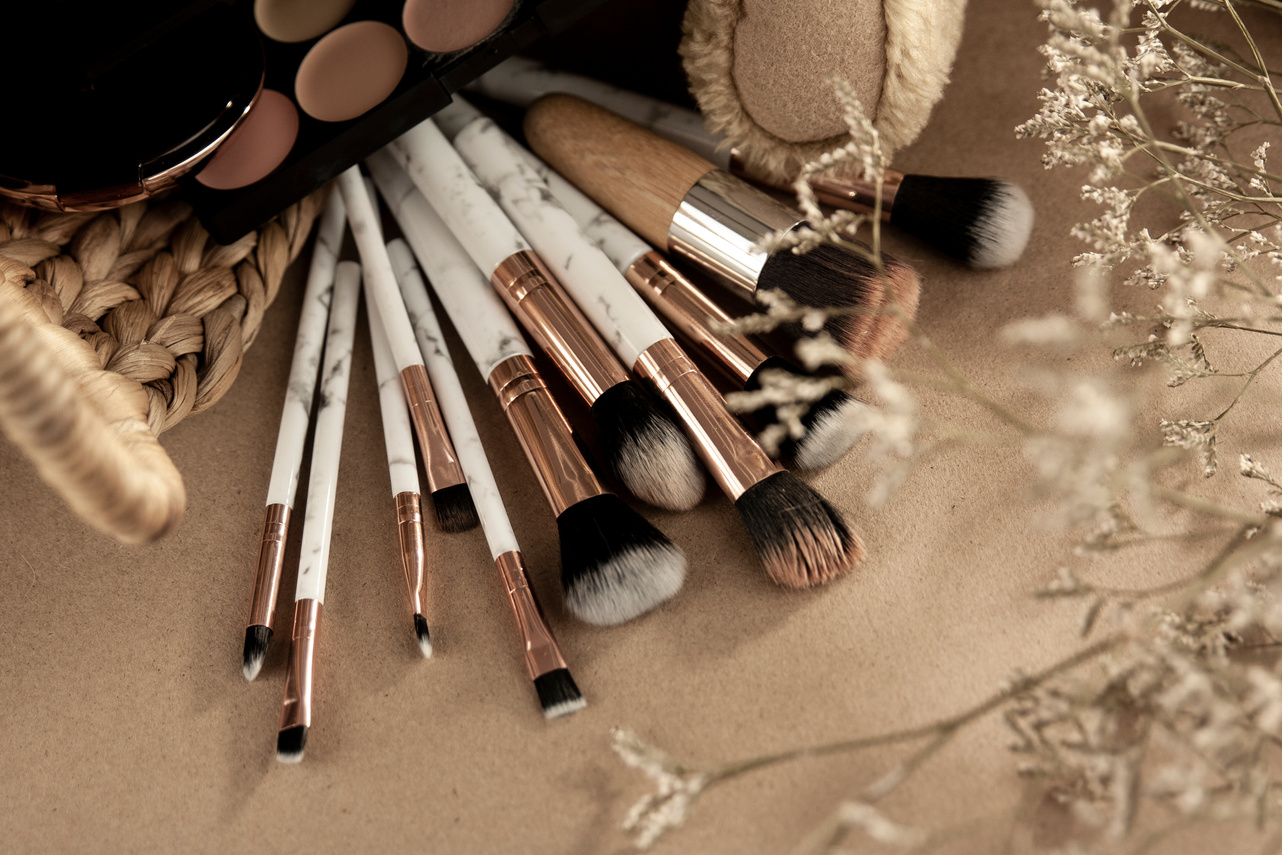 Makeup brushes with eyeshadows on beige surface